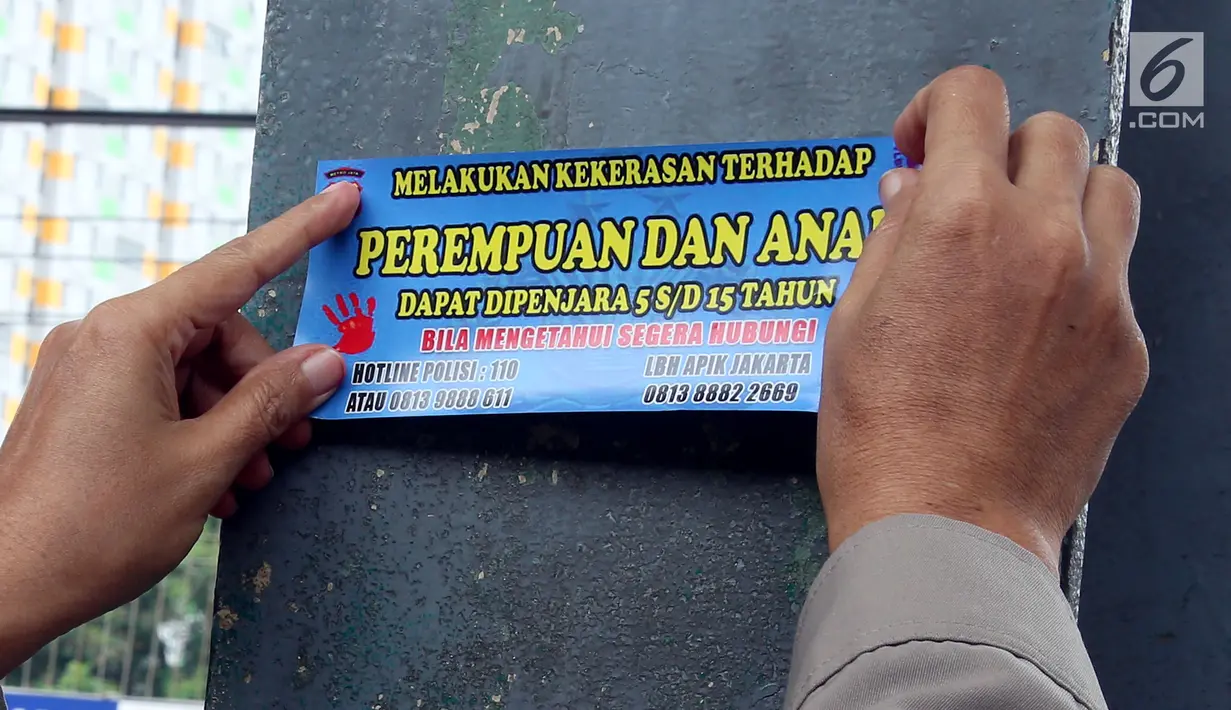 Petugas dari Polda Metro Jaya menempelkan stiker informasi pengaduan kekerasan di sekitar Stasiun Tanah Abang, Jakarta, Kamis (21/12). Stiker itu juga berisi informasi hukuman bagi pelaku tindak kekerasan pada wanita dan anak. (Liputan6.com/JohanTallo)