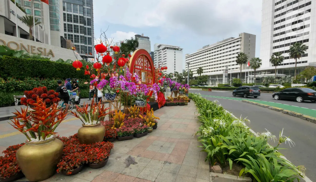 Kendaraan dan pejalan kaki melintasi ornamen dengan nuansa Imlek di kawasan Bundaran HI, Jakarta, Sabtu (29/1/2022). Ornamen yang didominasi warna merah dan emas ini dipasang dalam rangka menyambut perayaan Tahun Baru Imlek 2573, yang jatuh pada 1 Februari mendatang. (Liputan6.com/Herman Zakharia)