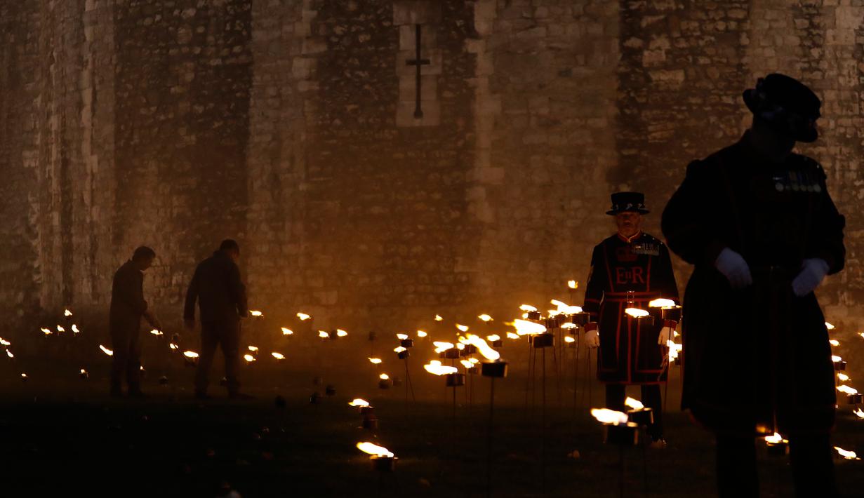 Yeoman Warders atau 'Beefeaters' menyalakan ribuan lilin di parit kering Tower of London, Inggris, Selasa (6/11). Nyala lilin membentuk instalasi yang disebut 'Beyond the Deepening Shadow: The Tower Remembers'. (AP Photo/Alastair Grant)