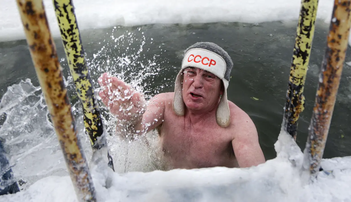 Seorang pria keluar dari air es setelah berenang selama hari yang membekukan di kota Omsk di Siberia, Rusia, Sabtu (26/12/2020). Suhu di Omsk turun hingga -32 derajat Celcius atau -25,6 derajat Fahrenheit. (AP Photo/Evgeniy Sofiychuk)