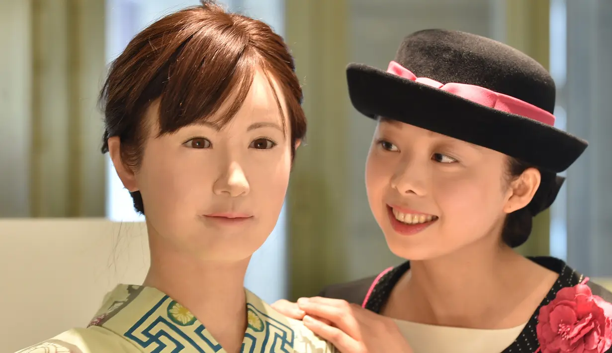 Seorang pengunjung berpose bersama robot humanoid ChihiraAico (kiri) yang mengenakan kimono Jepang di Tokyo pada 20 April 2015. Robot ini bisa tersenyum, menyanyi dan memberikan bimbingan pada pengunjung. (AFP PHOTO/KAZUHIRO)