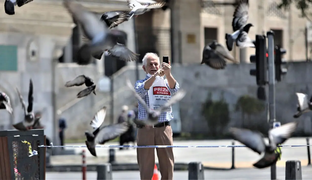 Seorang lansia mengabadikan gambar di Istanbul, Turki, Minggu (10/5/2020). Setelah melonggarkan lockdown terkait virus corona COVID-19, Turki mengizinkan para lansia berusia 65 tahun ke atas untuk keluar rumah.