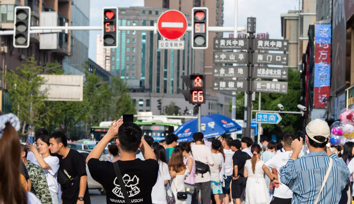 Orang-orang memandangi lampu lalu lintas berbentuk hati di Changsha, Provinsi Hunan, China, 25 Agustus 2020. Hal ini untuk mempromosikan budaya tradisional China sembari meminta publik untuk mematuhi peraturan lalu lintas di Festival Qixi. (Xinhua/Chen Sihan)