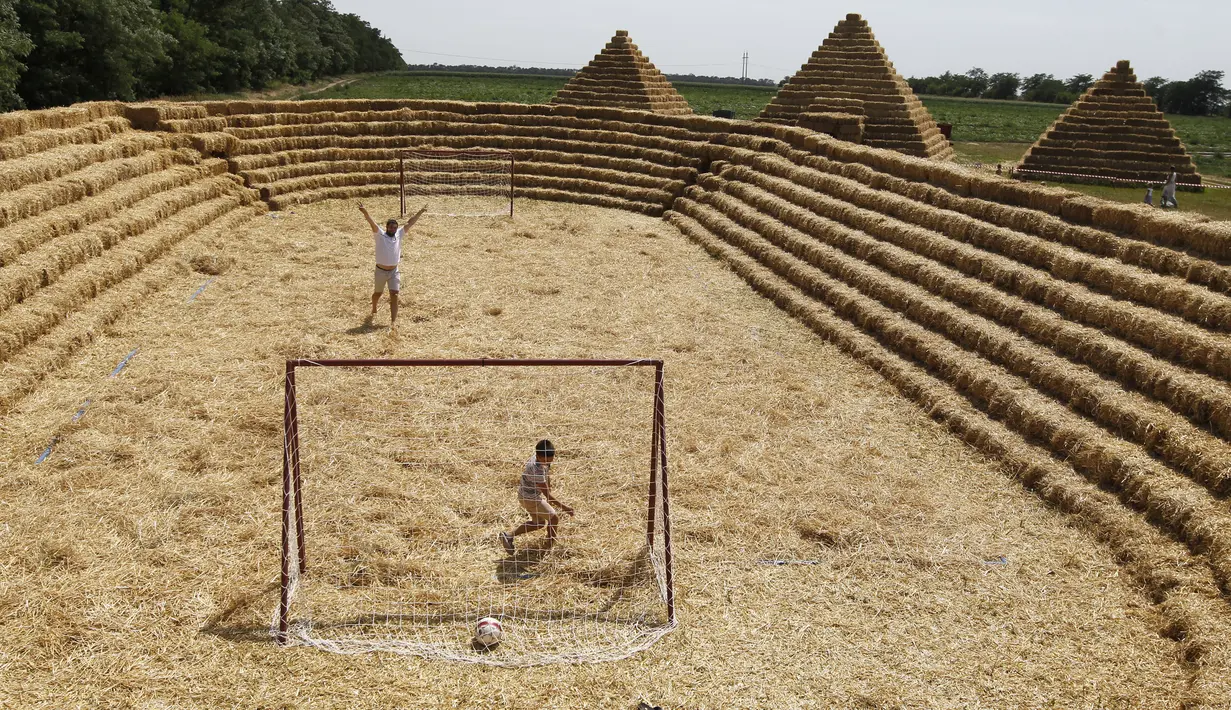 Anak-anak bermain sepak bola di stadion yang ada di taman jerami, wilayah pertanian Ponomaryovo, di Rusia, Rabu (19/7). Taman jerami tersebut dibangun oleh penduduk setempat untuk meningkatkan daya tarik wisatawan. (REUTERS/Eduard Korniyenkov)