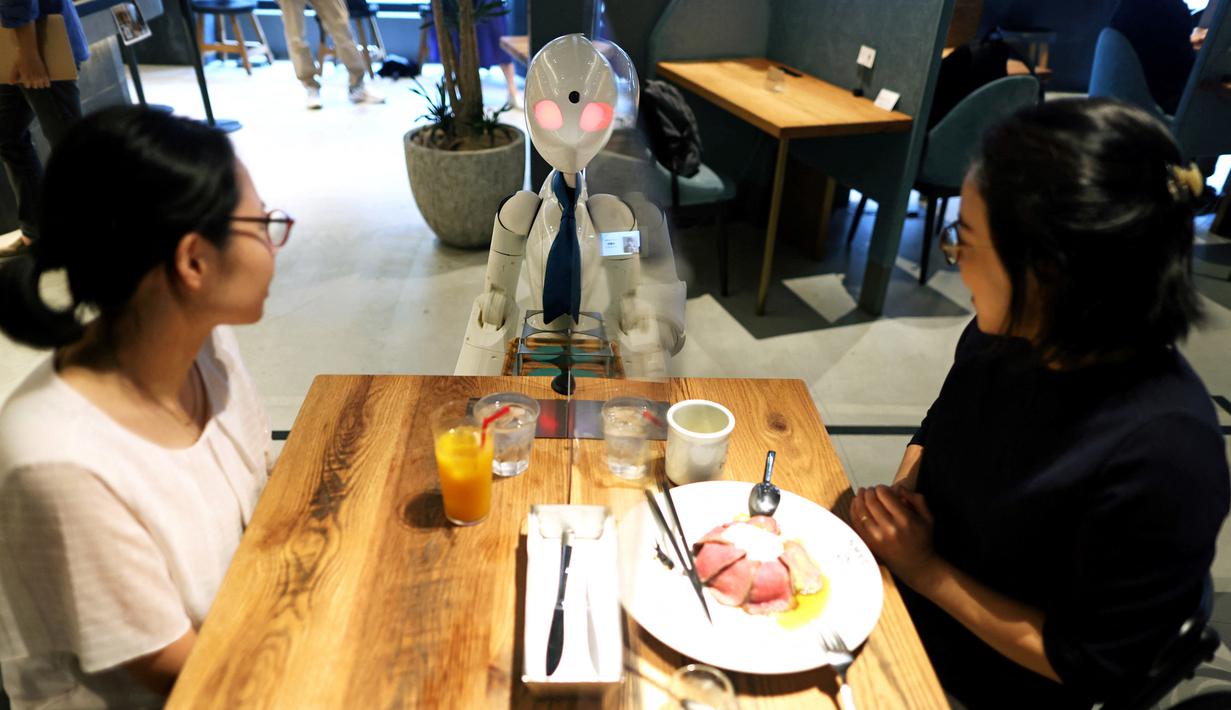 Robot humanoid mengantarkan minuman kepada pelanggan di Dawn Cafe, Tokyo, Jepang, 17 Agustus 2021. Peluncuran kafe ini bersamaan dengan Paralimpiade yang akan dibuka pada 24 Agustus. (Behrouz MEHRI/AFP)