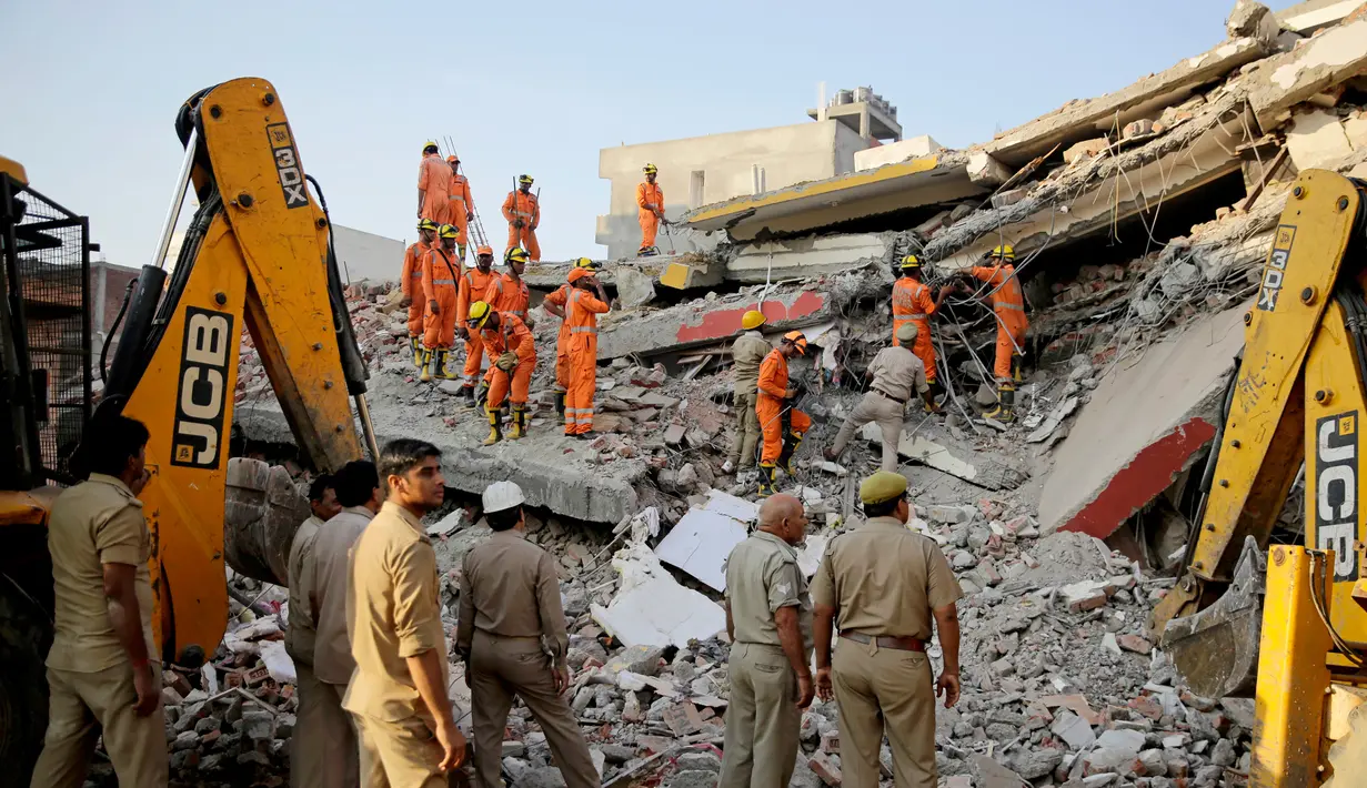 Tim penyelamat mencari korban yang terjebak reruntuhan gedung enam lantai yang ambruk di desa Shahberi, pinggiran kota New Delhi, India, Rabu (18/7). Peralatan berat  digunakan untuk mencari para korban. (AP Photo/Altaf Qadri)