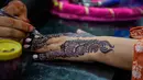 Seorang ahli kecantikan melukis 'Henna' tradisional di tangan pelanggan untuk perayaan Idul Fitri, yang menandai berakhirnya bulan suci Ramadan, di Rawalpindi, Pakistan, Rabu 18 Maret 2026. (AP Photo/Anjum Naveed)