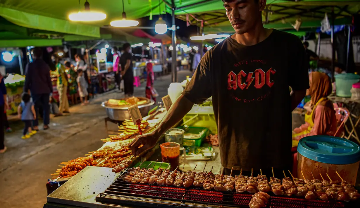 <p>Penjual makanan jalanan mendirikan kios mereka untuk menjual makanan kepada umat Muslim untuk berbuka puasa selama bulan suci Ramadhan di pasar malam di provinsi Narathiwat, Thailand selatan (21/4/2022). (AFP/Madaree Tohlala)</p>