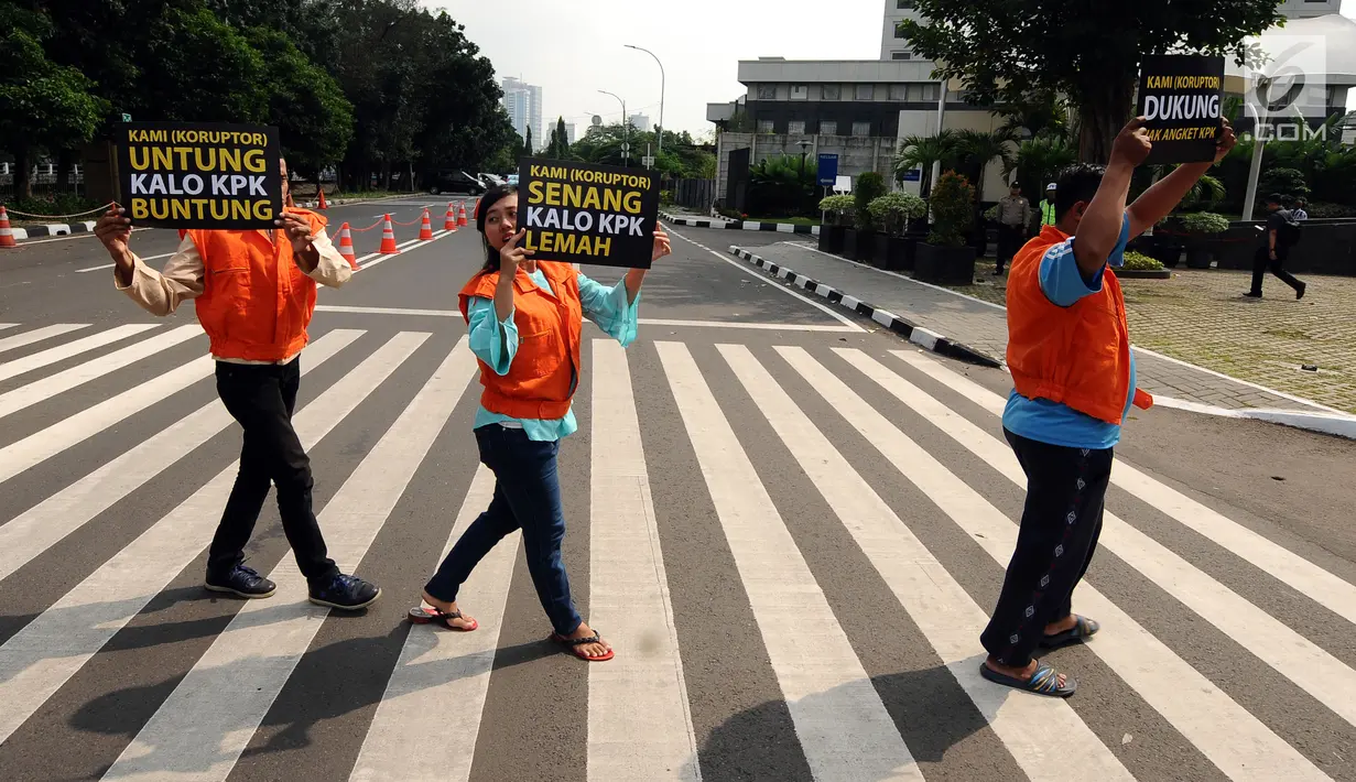Aktivis mengangkat tulisan bertema satir usai memparodikan adegan pertemuan anggota Pansus Hak Angket KPK dengan narapidana kasus korupsi di depan Gedung KPK, Jakarta, Minggu (9/7). Mereka mengkritisi pertemuan tersebut. (Liputan6.com/Helmi Fithriansyah)