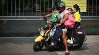 Seorang wanita menjemput anak-anaknya dari sekolah lebih awal karena polusi di Bangkok (30/1). Meningkatnya partikel berbahaya yang dikenal dengan PM 2,5 akhir Desember lalu membuat 437 sekolah di Bangkok tak beroperasi. (AFP Photo/Lillian Suwanrumpha)