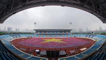 Para peserta mengangkat kain warna-warni untuk membentuk bendera Vietnam selama acara yoga massal di Stadion Nasional My Dinh di Hanoi pada 12 Agustus 2023. (Tien TUAN/AFP)