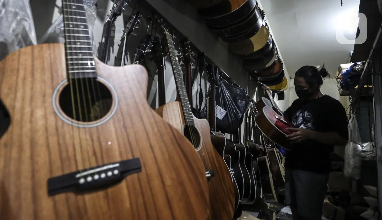 Harry memeriksa gitar klasik saat akan direparasi menjadi gitar listrik di toko kawasan Kedoya, Jakarta Barat, Selasa (9/2/2021). Turunnya servis gitar selama pandemi COVID-19 dikarenakan banyak pemilik gitar enggan untuk keluar rumah dan memilih untuk membeli gitar baru. (Liputan6.com/Johan Tallo)