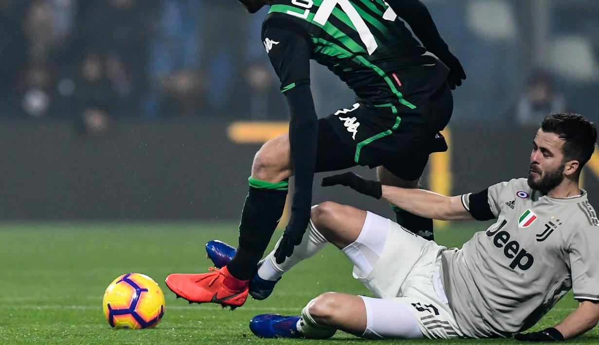 Miralem Pjanic mencoba menghentikan pergerakan Manuel Locatelli pada laga lanjutan Serie A yang berlangsung di stadion Mapei, Reggio Emilia, Senin (11/2). Juventus menang 3-0 atas Sassuolo. (AFP/Miguel Medina)