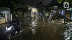 Warga melintas di genangan banjir di kawasan Mampang Prapatan, Jakarta, Sabtu (13/11/2021). Intensitas hujan yang tinggi sejak sore di Jakarta membuat kawasan permukiman di Mampang Prapatan tergenang banjir dengan tinggi sebetis orang dewasa. (Liputan6.com/Faizal Fanani)