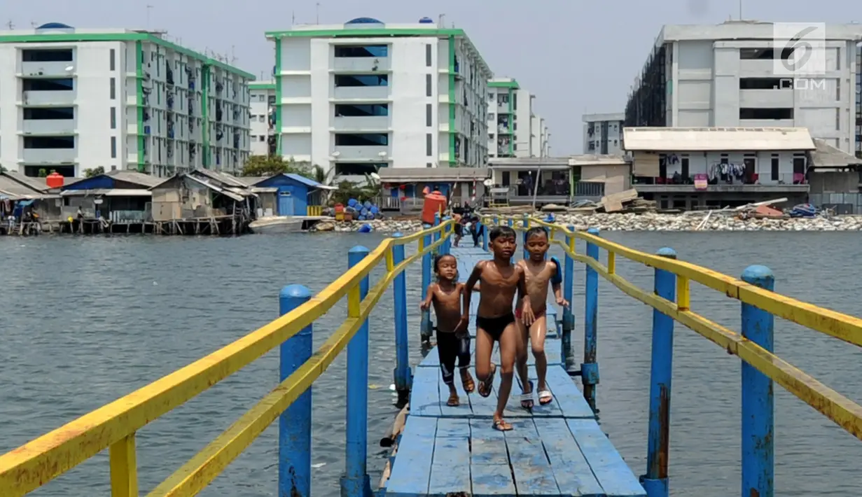 Sejumlah anak bermain pada jembatan kayu yang melintasi tanggul laut Muara Baru di Penjaringan, Jakarta Utara, Minggu (1/9/2019). Anak-anak memanfaatkan sisi tanggul laut raksasa (giant sea wall) sebagai   tempat  bermain alternatif. (merdeka.com/Arie Basuki)