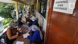 Petugas kesehatan dari Puskesmas Kecamatan Matraman melakukan skrining saat vaksinasi COVID-19 di SD Negeri 25 Utan Kayu Selatan, Matraman, Jakarta Timur, Rabu (23/3/2022). Vaksin yang digunakan adalah vaksin AstraZeneca untuk dosis pertama, kedua dan ketiga (booster). (Liputan6.com/Herman Zakharia)