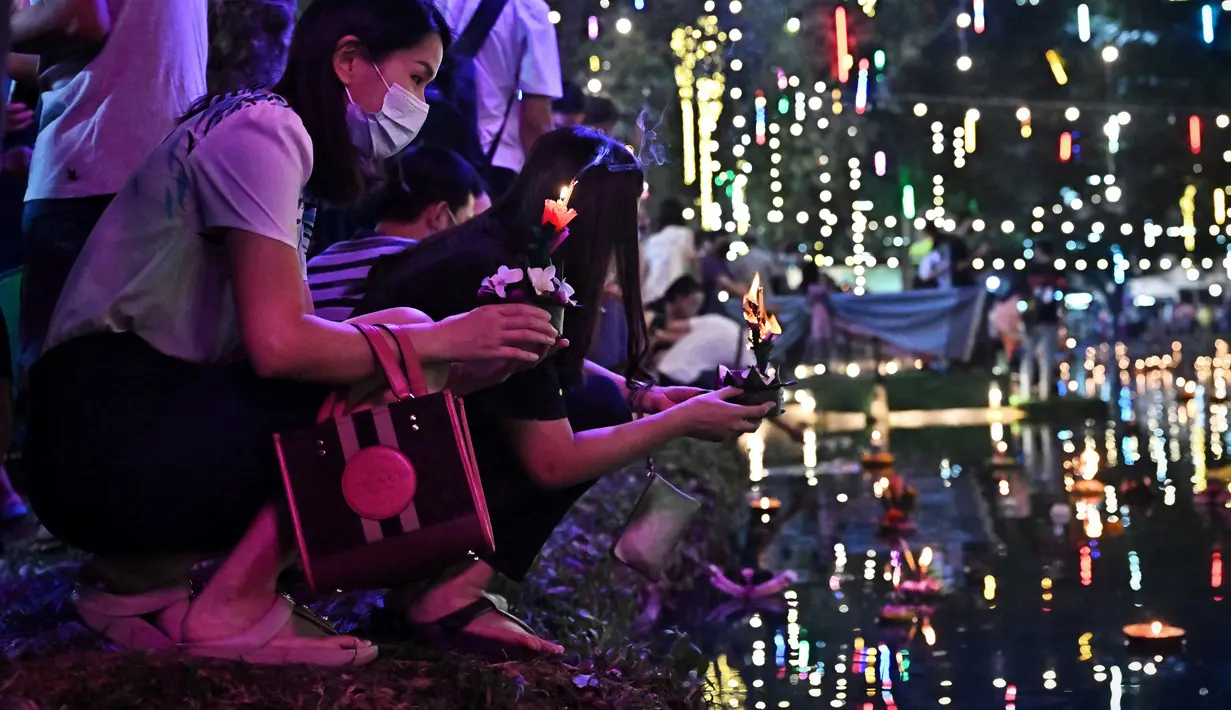 Orang-orang melepaskan lampion mengambang di kolam selama festival Loy Krathong di Bangkok (8/11/2022). Loy Krathong dirayakan setiap tahun di seluruh Thailand sebagai penghormatan kepada dewi air. (AFP/Lillian Suwanrumpha)