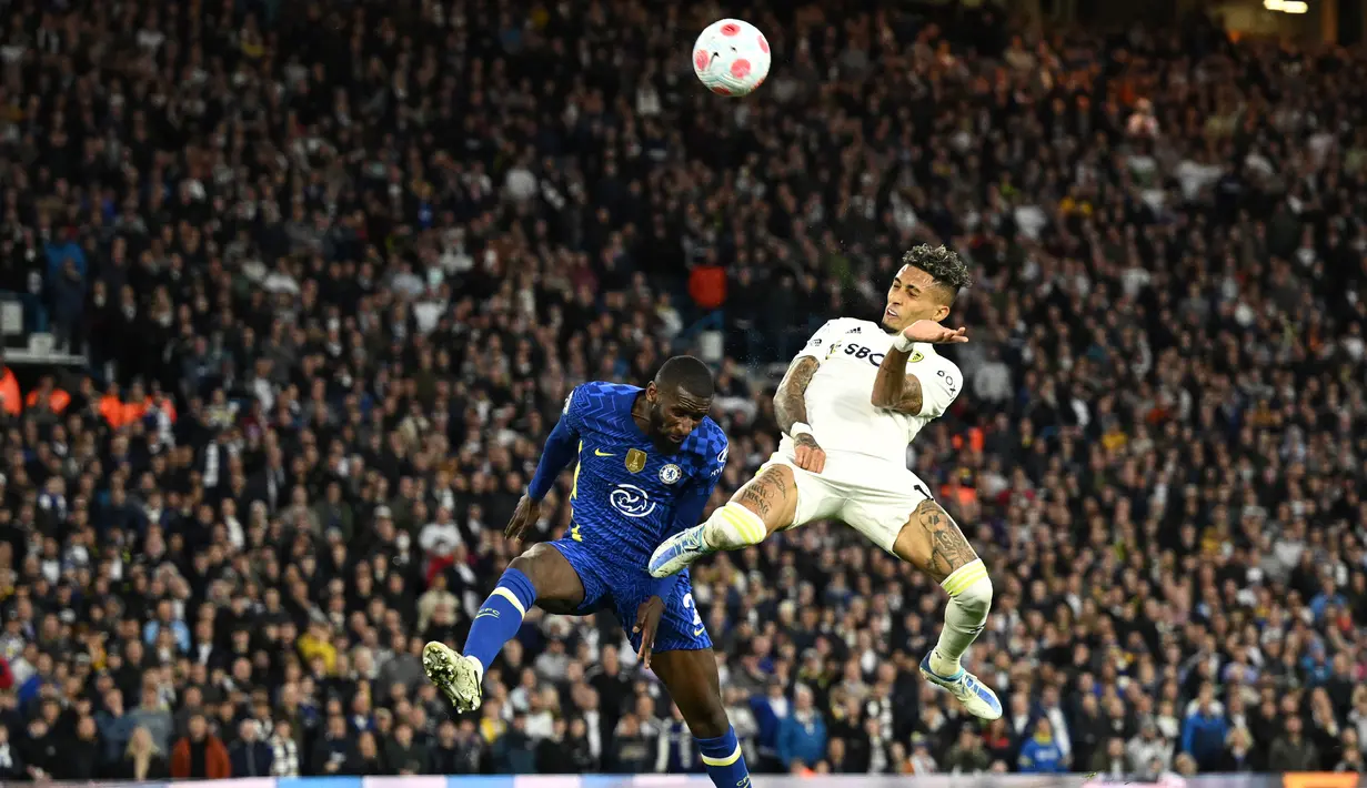 <p>Gelandang Leeds United Raphinha Dias Belloli (kanan) berebut bola dengan bek Chelsea Antonio Rudiger (kiri) dalam laga tunda pekan ke-33 Liga Inggris 2021/2022 di Stadion Elland Road, Kamis (12/5/2022) dini hari WIB. Chelsea menang telak 3-0 atas Leeds United. (Oli SCARFF / AFP)</p>