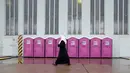 Seorang wanita berjalan melewati deretan toilet portable di tempat penampungan bagi para migran di dalam hanggar bekas bandara Tempelhof di Berlin, Jerman, Rabu (9/12/2015). (REUTERS/Fabrizio Bensch)