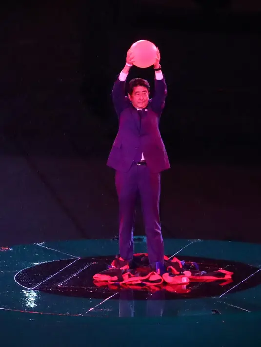 PM Jepang, Shinzo Abe ambil bagian dalam penyerahan bendera Olimpiade pada upacara penutupan Olimpiade Rio 2016 di Rio de Janeiro, Minggu (21/8). Shinzo Abe sempat menyamar menjadi Mario Bros untuk mempromosikan Olimpiade Tokyo 2020. (Yves Herman/AFP)