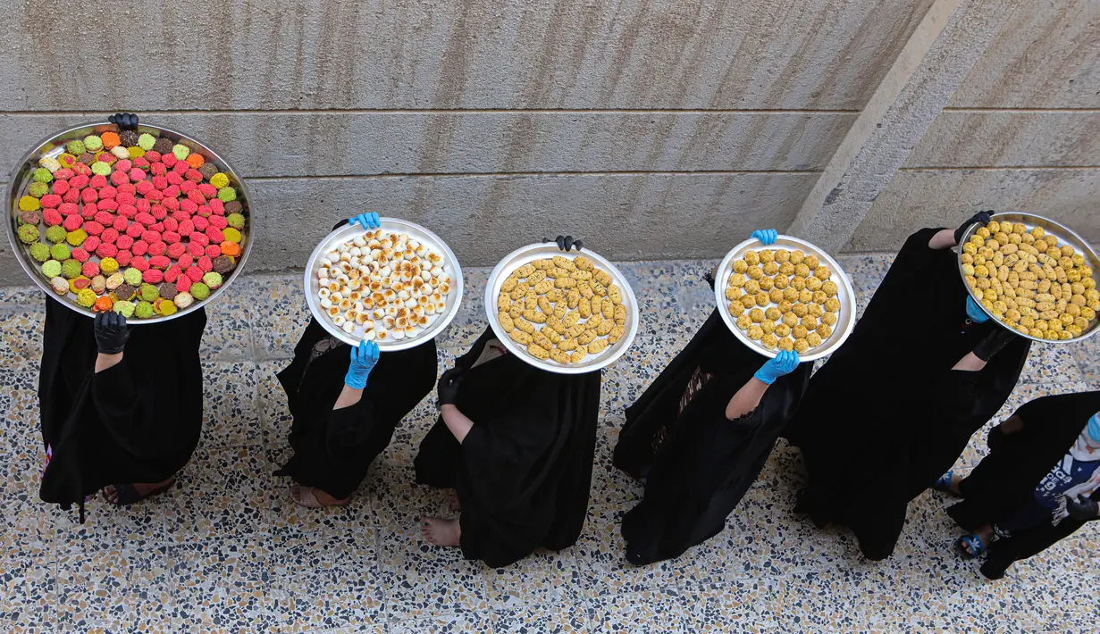 Sejumlah perempuan membawa kue untuk perayaan Idul Fitri yang akan datang di Basra, Irak, Jumat (22/5/2020). Idul Fitri menandai berakhirnya bulan suci Ramadan. (AP Photo/Nabil al-Jurani)