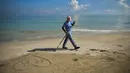 Seorang pekerja dengan mengenakan masker membersihkan pantai di Havana pada Senin (15/6/2020). Kuba akan menguji semua pelancong untuk Covid-19 dan membatasi kontak mereka dengan penduduk setempat ketika perbatasan dibuka kembali untuk turis asing. (Yamil LAGE / AFP)