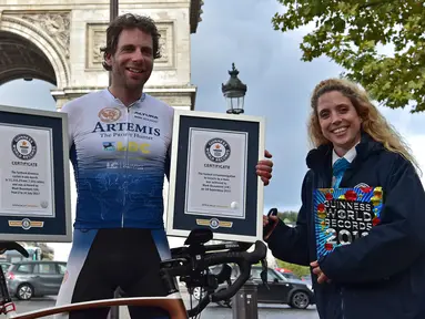 Pembalap sepeda Inggris, Mark Beaumont (34) berpose dengan sertifikat Guinness World Records setibanya di Arc de Triomphe, Paris, setelah menyelesaikan tur keliling dunia dalam waktu 78 hari, Senin (18/9). (CHRISTOPHE ARCHAMBAULT / AFP)