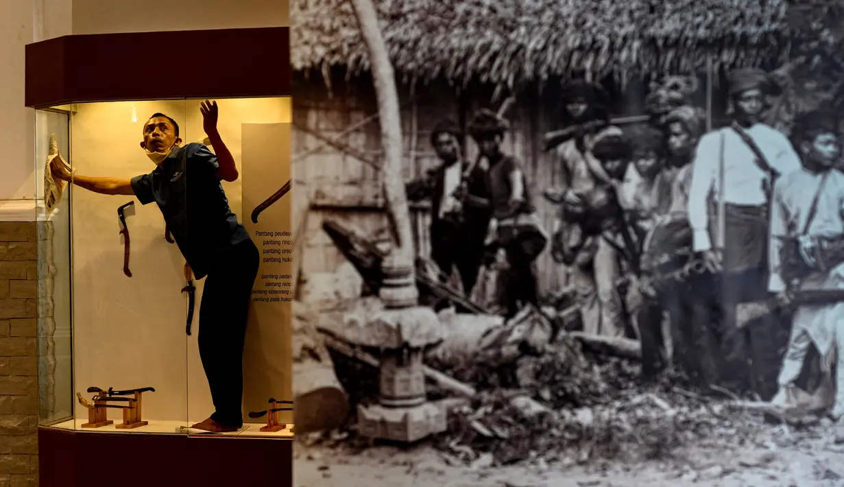 Seorang pekerja membersihkan etalase yang memajang rencong jelang pameran persenjataan tradisional di Museum Aceh, Banda Aceh, Aceh, Jumat (15/10/2021). Senjata yang dipamerkan mulai dari siwaih, rencong, keris, pedang, tombak, meriam, perisai dan masih banyak lainnya. (CHAIDEER MAHYUDDIN/AFP)