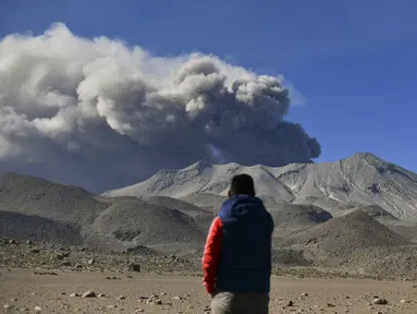 Seorang pria menyaksikan tumpukan asap dan abu naik dari kawah gunung berapi Ubinas, yang terletak di wilayah Moquegua di Peru selatan, pada 5 Juli 2023. (Diego Ramos / AFP)
