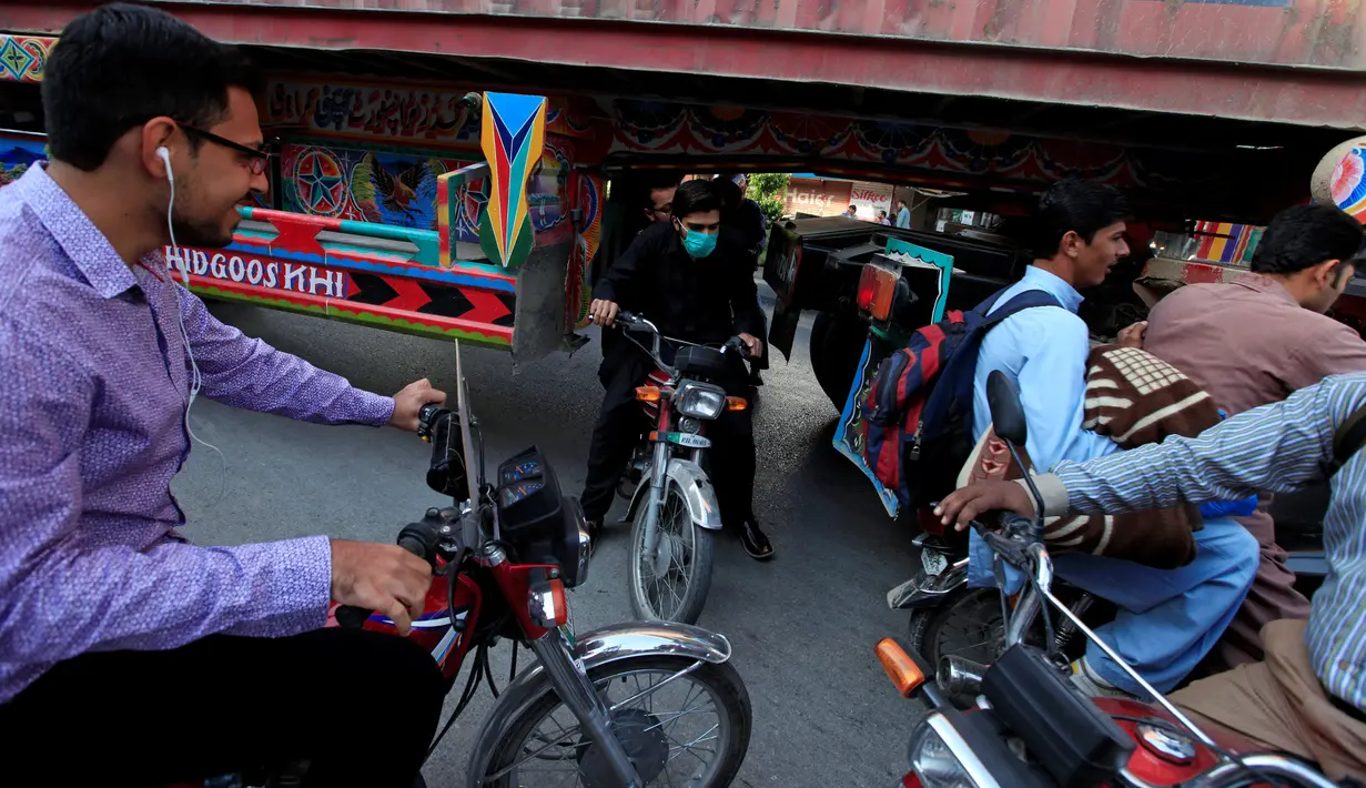 Sejumlah pengendara motor melewati kolong sebuah truk kontainer di Rawalpindi, Pakistan (28/10). Tanpa rasa takut para pengendara motor tersebut melintasi kolong truk yang membawa peti kemas. (Reuters/Faisal Mahmood)