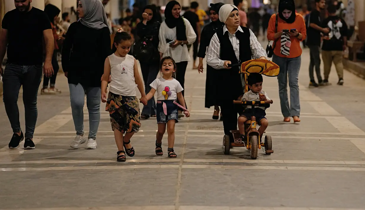 Warga Irak berjalan melalui pasar buku di Jalan Mutanabi Baghdad, Irak (18/5/2022). Kini Jalan Al-Mutanabbi dilengkapi dengan pameran seni, pembukaan galeri, festival buku dan festival lain. (AP Photo/Hadi Mizban)