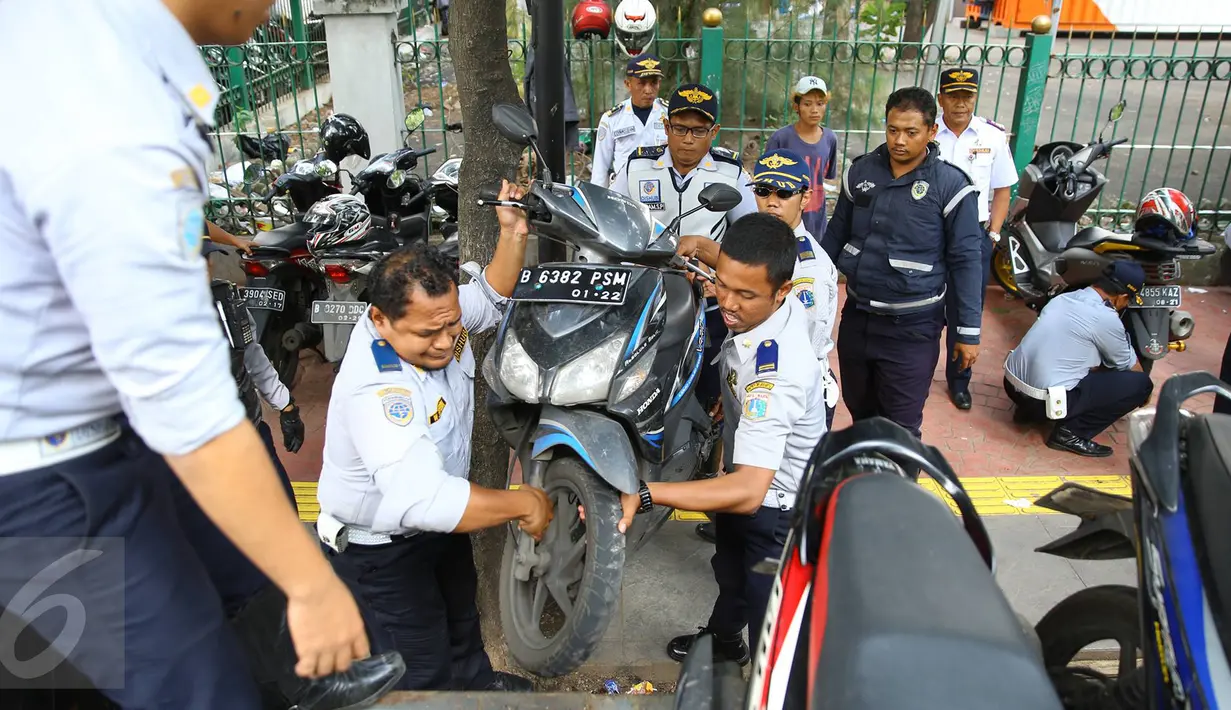 Petugas Dishub menertibkan sepeda motor yang parkir di sepanjang trotoar kawasan Kebon Sirih, Jakarta, Rabu (18/1). Puluhan motor diamankan serta digembosi dalam penertiban tersebut karena menutupi jalur pedestrian. (Liputan6.com/Immaniel Antonius)