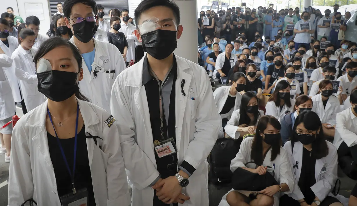 Perawat dan staf medis mengenakan penutup mata dan masker saat unjuk rasa di sebuah rumah sakit di Hong Kong (13/8/2019). Mereka memprotes kebrutalan polisi yang menurut mereka terjadi selama demonstrasi anti-pemerintah berlangsung pada akhir pekan. (AP Photo/Kin Cheung)