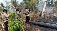 Personel Polda Riau mendinginkan bekas kebakaran lahan agar apinya tidak menyala lagi. (Liputan6.com/M Syukur)