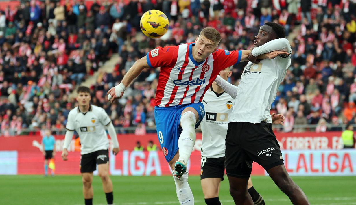 Pemain Girona, Artem Dovbyk (tengah) beduel dengan pemain Valencia, Mouctar Diakhaby pada laga lanjutan Liga Spanyol 2023/2024 di Montilivi Stadium, Girona, Spanyol, 1 Desember 2023. (AFP/Lluis Gene)