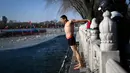Seorang pria bersiap untuk berenang di sebuah danau yang airnya sebagian membeku di Beijing pada Senin (30/12/2019). Penduduk lokal banyak menggemari kebiasaan berenang di musim dingin dimana banyak sungai dan danau-danau mulai membeku. (WANG ZHAO / AFP)