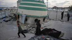 Mereka larut dalam kebersamaan yang penuh haru dan sukacita meski berada di tengah reruntuhan akibat konflik yang berkepanjangan. Tampak dalam foto, Khadija Suleiman menyiapkan makanan untuk iftar keluarganya, yaitu hidangan berbuka puasa selama bulan suci Ramadhan, di reruntuhan masjid tempat mereka saat ini berlindung di Deir al-Balah, Jalur Gaza, Jumat 6 Maret 2026. (AP Photo/Abdel Kareem Hana)