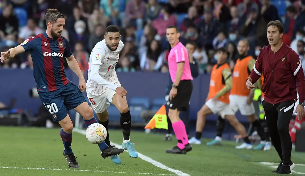 <p>Pemain Sevilla Youssef En-Nesyri (kedua kiri) berebut bola dengan pemain Levante Jorge Miramon sebelah pelatih Sevilla Julen Lopetegui pada pertandingan Liga Spanyol di Stadion Ciutat de Valencia, Valencia, Spanyol, 21 April 2022. (Jose Jordan/AFP)</p>
