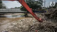 Pekerja kebersihan mengangkat sampah yang menumpuk di pintu air Manggarai, Jakarta, Selasa (22/9/2020). Tingginya curah hujan membuat kiriman sampah menumpuk di pintu air Manggarai. (Liputan6.com/Faizal Fanani)