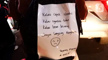 Sebuah kalimat menghiasi bagian belakang pemudik yang menggunakan sepeda motor di Jalan Raya Kalimalang, Bekasi, Jawa Barat, Rabu (19/4/2023) malam. (Liputan6.com/Herman Zakharia)