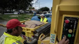 Masalah ini disebabkan oleh kapasitas yang terbatas dan sering terjadi penumpukan sampah, meskipun ada upaya daur ulang yang sedang dilakukan. Tampak dalam foto, pekerja pemerintah daerah mengumpulkan bahan daur ulang di desa Acharavi, pulau Corfu, pada 15 Oktober 2025. (Angelos TZORTZINIS/AFP)