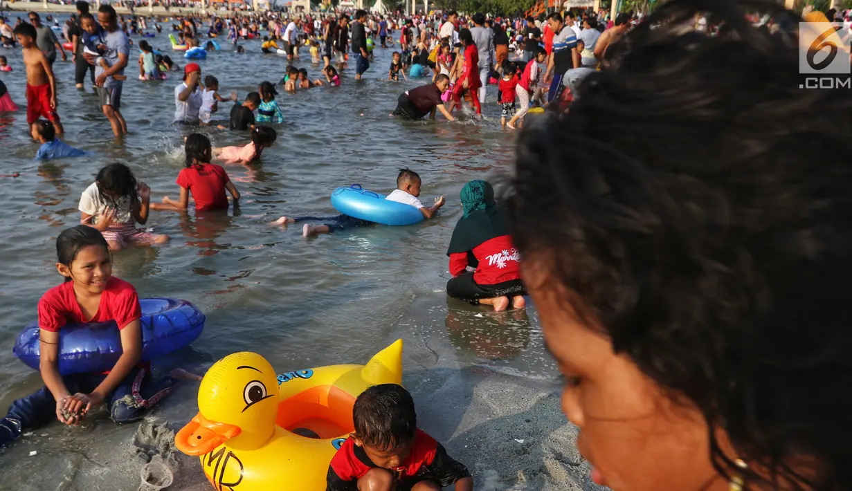 Pengunjung bermain dan berenang di kawasan Beach Pool, Taman Impian Jaya Ancol, Jakarta, Kamis (6/6/2019). Hari kedua Lebaran banyak dimanfaatkan warga untuk berlibur dan berekreasi bersama keluarga atau kerabat dengan mengunjungi pantai Ancol. (Liputan6.com/Johan Tallo)