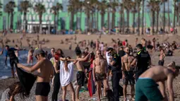 Petugas polisi meminta orang-orang untuk tidak duduk sambil berpatroli di pantai di Barcelona, Spanyol, Rabu, (20/5/2020). Berjemur dan berenang masih tidak diizinkan di pantai tersebut.  (AP Photo/Emilio Morenatti)