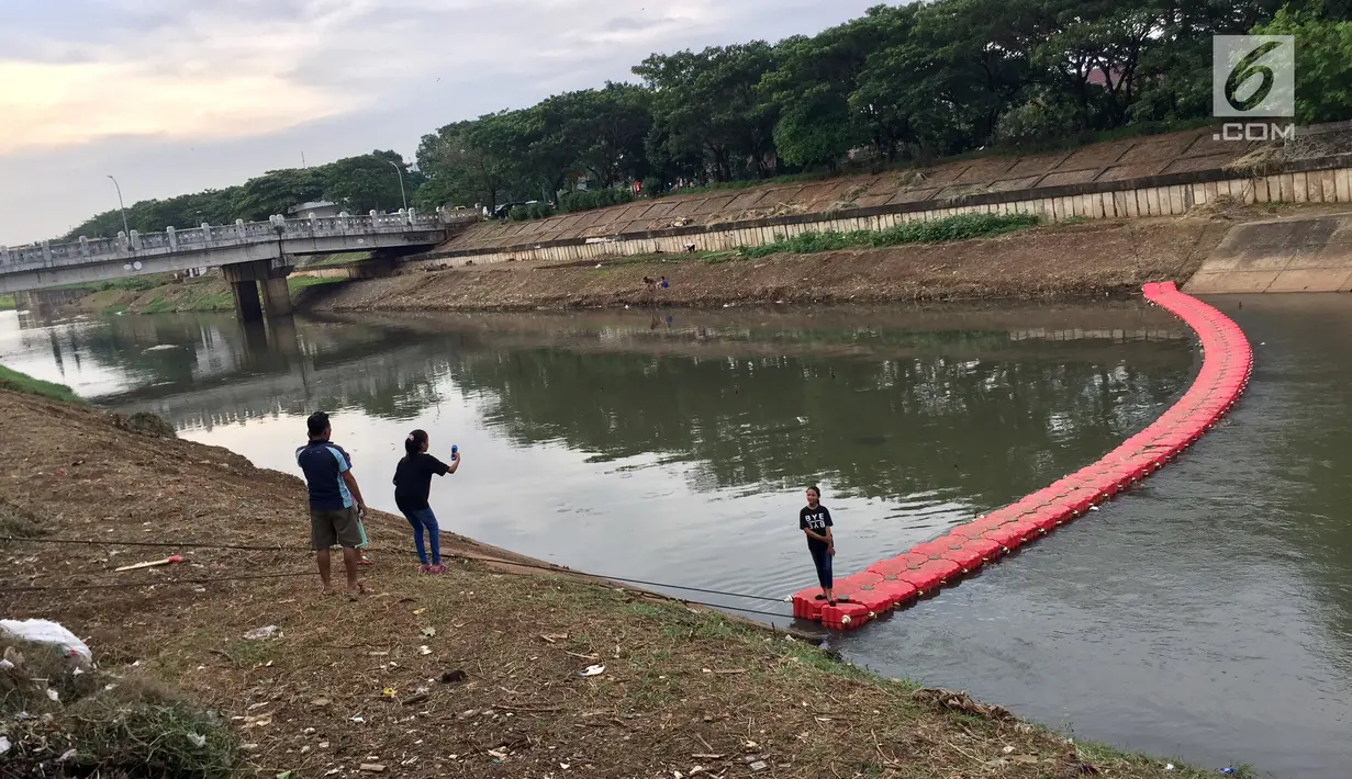 Seorang anak berfoto di penyaring sampah yang dijadikan jembatan di Kanal Banjir Timur di Jakarta, Kamis (28/12). Penyaring sampah yang berupa pelampung tersebut dimanfaatkan warga sebagai sarana untuk menyeberang. (Liputan6.com/Immanuel Antonius)