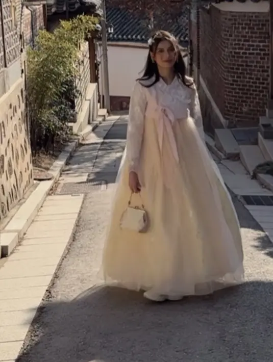 Sabrina memilih hanbok dengan warna kuning di bagian rok dan putih di bagian atas dengan aksen pita pink. [@sabrinachairunnisa_]