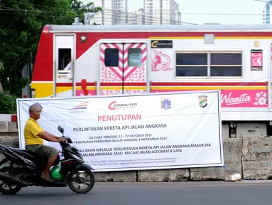 Warga melintas di depan spanduk sosialisasi penutupan perlintasan kereta di Jalan Angkasa, Jakarta, Minggu (15/10). Penutupan secara permanen perlintasan KA di Jalan Angkasa akan dilakukan pada 3 November mendatang. (Liputan6.com/Helmi Fithriansyah)
