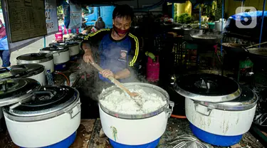 Petugas Taruna Siaga Bencana (Tagana) memasak nasi di Dapur Umum Kementerian Sosial di GOR Otista, Jakarta, Minggu (21/2/2021). Dalam sehari, petugas menyiapkan hingga 6.000 paket nasi kotak yang didistribusikan ke 11 kelurahan terdampak banjir. (Liputan6.com/Faizal Fanani)