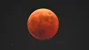 Blood moon terlihat saat gerhana bulan total di Goyang, barat laut Seoul, pada 8 November 2022. Fenomena gerhana bulan total terjadi pada 8 November 2022 di berbagai negara. (AFP/Jung Yeon-Je)