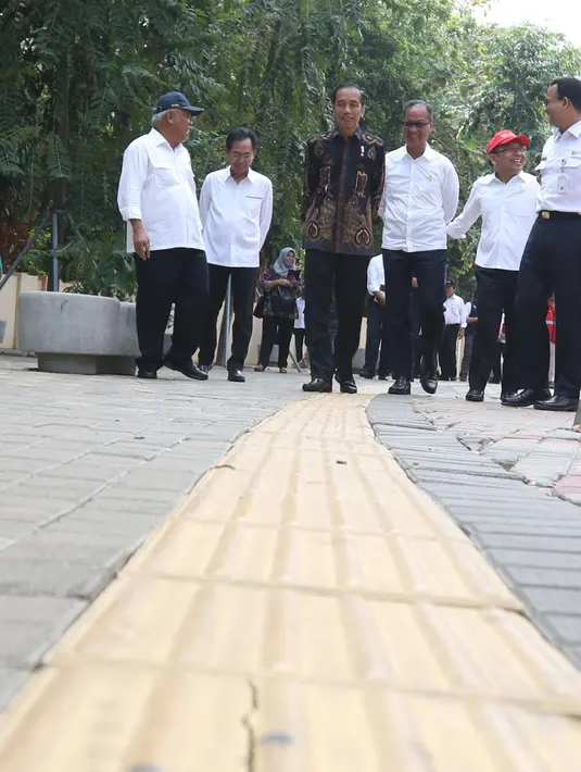 Presiden Joko Widodo (Jokowi) melihat kondisi fasilitas jalur penuntun dan petunjuk bagi disabilitas di Kompleks Gelora Bung Karno, Senayan, Selasa (16/10). Jokowi didampingi sejumlah menteri dan Gubernur DKI Anies Baswedan. (Liputan6.com/Angga Yuniar)