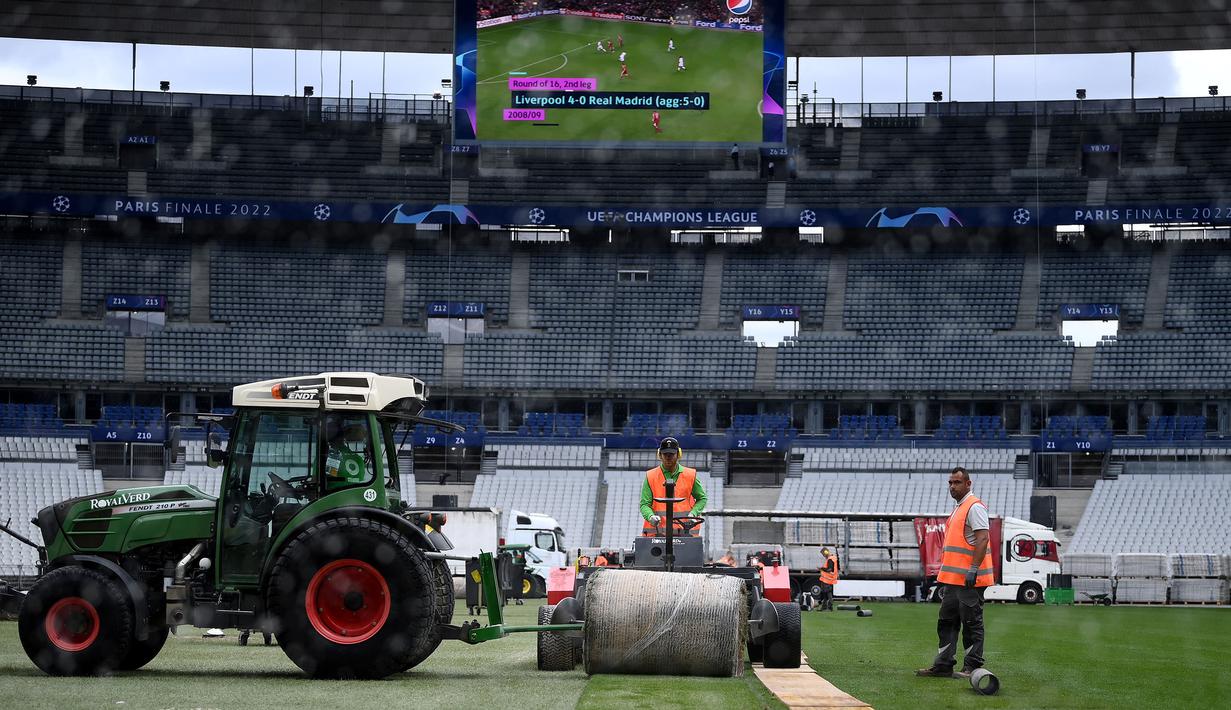 Sejumlah pekerja sedang memasang rumput hybrid baru di Stade de France, Saint-Denis, pada 24 Mei 2022 waktu setempat. Dalam waktu 48 jam, rumput baru yang ditanam di luar Barcelona, dipasang di Stade de France untuk pertandingan final Liga Champions antara Real Madrid dan Liverpool yang dijadwalkan berlangsung pada 28 Mei 2022. (AFP/Franck Fife)